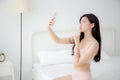 Beautiful young asian woman sexy in underwear talking a selfie on smartphone for social network in the bedroom. Royalty Free Stock Photo