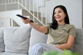 Beautiful young asian woman sits on couch enjoy watching TV show in the living room Royalty Free Stock Photo