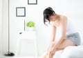 Beautiful young asian woman sitting on a bed stroking legs with soft smooth skin in the bedroom Royalty Free Stock Photo