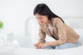 Beautiful young asian woman sitting on bed using laptop computer working from home in the bedroom. Royalty Free Stock Photo