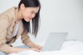 Beautiful young asian woman sitting on bed using laptop computer working from home in the bedroom. Royalty Free Stock Photo