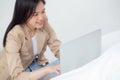 Beautiful young asian woman sitting on bed using laptop computer working from home in the bedroom. Royalty Free Stock Photo