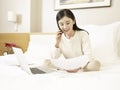 Young asian woman talking on cellphone on bed Royalty Free Stock Photo