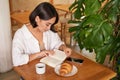 Beautiful young asian woman sitting in cafe with a book, eating croissant and reading, drinking cup of coffee Royalty Free Stock Photo