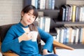 Beautiful young asian woman sitting on chair with comfort and relaxing in living room at home drinking a cup of coffee Royalty Free Stock Photo