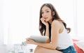 Beautiful young Asian woman sitting on her bed in the morning and reading book and looking at camera. Enjoying free and Relax Royalty Free Stock Photo