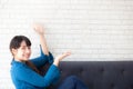 Beautiful young asian woman sitting and smiling happy and presenting something on sofa showing future Royalty Free Stock Photo