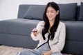 Beautiful young asian woman sitting using remote control with television for watching series with cozy. Royalty Free Stock Photo