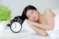 Beautiful young asian woman sleep with relax on the bed with alarm clock in the morning. Royalty Free Stock Photo
