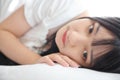 Beautiful young Asian woman sleeping on bed relaxing in the morning light with white room Royalty Free Stock Photo