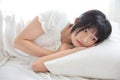 Beautiful young Asian woman sleeping on bed relaxing in the morning light with white room Royalty Free Stock Photo