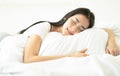 Beautiful young Asian woman sleeping well in bed hug soft white pillow in the morning. Korean girl enjoying sweet dreams and Royalty Free Stock Photo