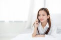 Beautiful young asian woman smiling lying and relax on the bed in the morning, girl using mobile Royalty Free Stock Photo