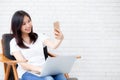 Beautiful young asian woman smiling and selfie with smartphone during work from home in living room. Royalty Free Stock Photo