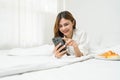 Beautiful young asian woman smiling sitting relax on the bed in the morning, girl using mobile smart phone talking enjoy Royalty Free Stock Photo
