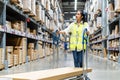 Beautiful young Asian woman staff worker pushing trolley or picking cart  to arrange things in warehouse store Royalty Free Stock Photo