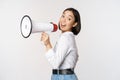 Beautiful young asian woman talking in megaphone, screams in speakerphone and smiling, making announcement, shout out Royalty Free Stock Photo