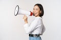 Beautiful young asian woman talking in megaphone, screams in speakerphone and smiling, making announcement, shout out Royalty Free Stock Photo