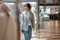 A beautiful young Asian woman in trendy clothes is walking in a shopping mall with her shopping bags Royalty Free Stock Photo