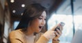Beautiful young Asian woman use smartphone in coffee shop, happy surprise smiling. People modern lifestyle, internet communication