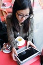 Beautiful young asian woman using her digital tablet while drinking coffee in coffee shop. Royalty Free Stock Photo