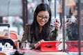 Beautiful young asian woman using her digital tablet while drinking coffee in coffee shop. Royalty Free Stock Photo