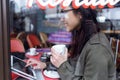 Beautiful young asian woman using her digital tablet while drinking coffee in coffee shop. Royalty Free Stock Photo