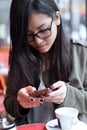 Beautiful young asian woman using her mobile phone in the terrace of a coffee shop. Royalty Free Stock Photo