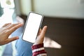 Female`s hand holding a mobile phone white screen mockup. close-up image Royalty Free Stock Photo