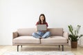 Beautiful Young Asian Woman Using Laptop While Sitting On Couch At Home Royalty Free Stock Photo