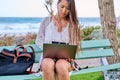 Beautiful young Asian woman using laptop sitting on an outdoor bench Royalty Free Stock Photo