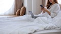 A beautiful young asian woman using mobile phone and laptop computer while lying down on bed Royalty Free Stock Photo