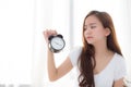 Beautiful young asian woman wake up in morning annoyed alarm clock holding hand Royalty Free Stock Photo