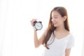 Beautiful young asian woman wake up in morning annoyed alarm clock holding hand Royalty Free Stock Photo