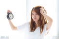 Beautiful young asian woman wake up in morning annoyed alarm clock holding hand, standing hurry wake late with appointment with c Royalty Free Stock Photo