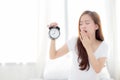 Beautiful young asian woman wake up in morning yawn and annoyed alarm clock holding hand Royalty Free Stock Photo