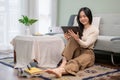 A beautiful Asian woman watching a movie on her digital tablet while relaxing in her living room Royalty Free Stock Photo