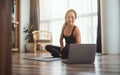 A beautiful young woman watching online workout tutorials on laptop at home