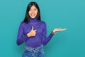 Beautiful young asian woman wearing casual clothes showing palm hand and doing ok gesture with thumbs up, smiling happy and Royalty Free Stock Photo