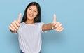 Beautiful young asian woman wearing casual white t shirt approving doing positive gesture with hand, thumbs up smiling and happy Royalty Free Stock Photo