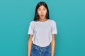 Beautiful young asian woman wearing casual white t shirt in shock face, looking skeptical and sarcastic, surprised with open mouth Royalty Free Stock Photo