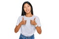 Beautiful young asian woman wearing casual white t shirt success sign doing positive gesture with hand, thumbs up smiling and Royalty Free Stock Photo