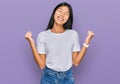 Beautiful young asian woman wearing casual white t shirt very happy and excited doing winner gesture with arms raised, smiling and Royalty Free Stock Photo