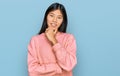 Beautiful young asian woman wearing casual winter sweater looking confident at the camera smiling with crossed arms and hand Royalty Free Stock Photo