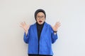 beautiful young asian woman wearing glasses, hijab and wearing blue blazer with surprised face gesture Royalty Free Stock Photo