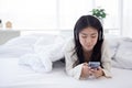 Beautiful young asian woman wearing headset using smartphone for music while relax on bed in bedroom. Royalty Free Stock Photo