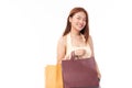Beautiful young Asian woman wearing a yellow tank top happily holds many shopping bags in her hand isolated on white background Royalty Free Stock Photo