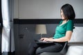 Beautiful young asian woman working on laptop while sitting on chair at home with flare light,Happy and smiling,Enjoying time Royalty Free Stock Photo