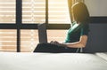 Beautiful young asian woman working on laptop while sitting on chair at home with flare light,Happy and smiling,Enjoying time Royalty Free Stock Photo