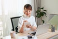 Beautiful young Asian woman writing notebook while working with laptop at home Royalty Free Stock Photo